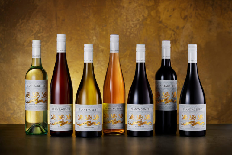 A lovely example of creative wine bottle photography. This is a group photo of wine bottles for Plantagenet Wines. it's the 7 bottles in the Three Lions range. They're standing in a group on a table top, and the golden background is backlit to achieve an elevated feel.